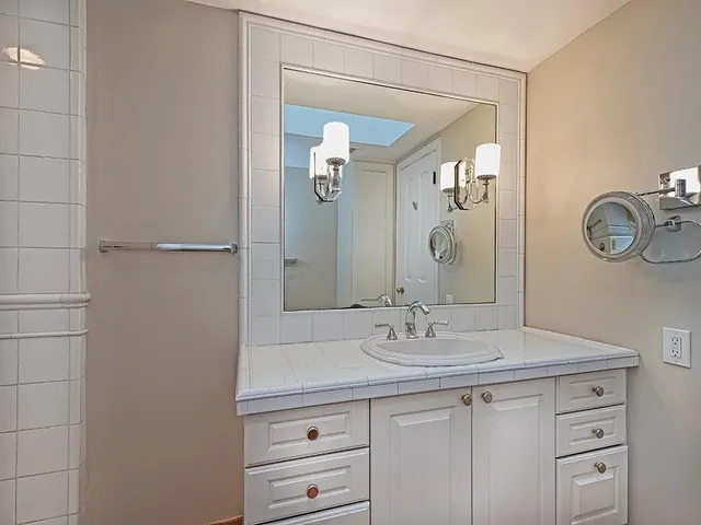a bathroom with a granite countertop sink a mirror and a shower