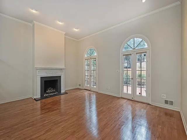 a view of an empty room with wooden floor fireplace and a window
