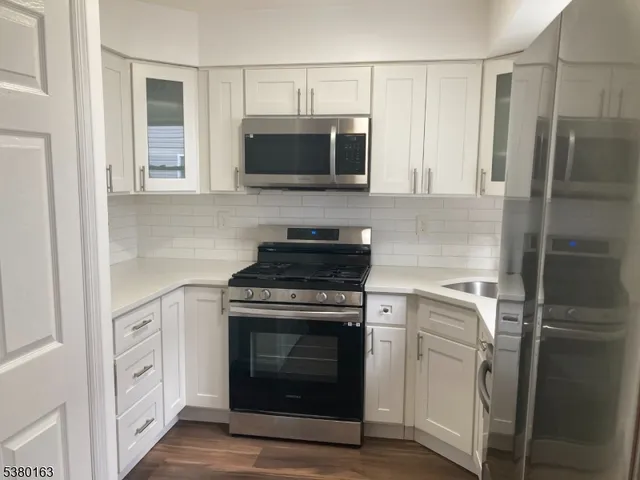 a kitchen with white cabinets and stainless steel appliances