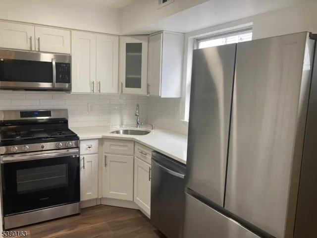 a kitchen with stainless steel appliances a refrigerator sink and microwave
