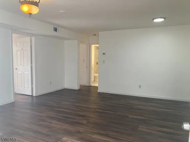 a view of an empty room with wooden floor and window
