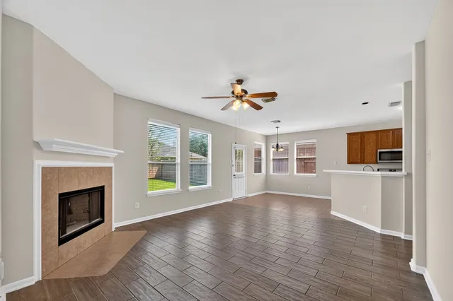 a view of an empty room with window and wooden floor