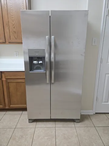 a close view of a refrigerator in kitchen and an empty room