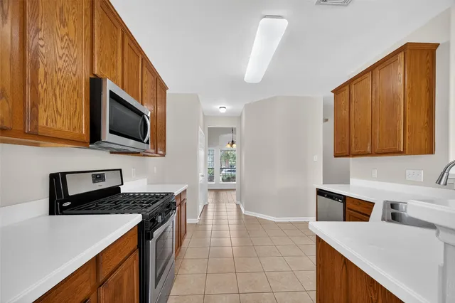 a kitchen with stainless steel appliances a stove a sink a microwave a refrigerator a cabinets and wooden floor