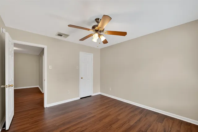 a view of a room with wooden floor and a ceiling fan