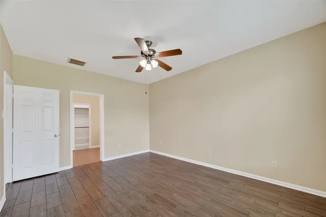 an empty room with wooden floor and ceiling fan