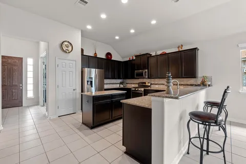a kitchen with stainless steel appliances granite countertop a refrigerator and a stove top oven