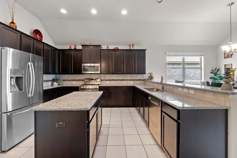 a kitchen with granite countertop a sink a counter space appliances and cabinets