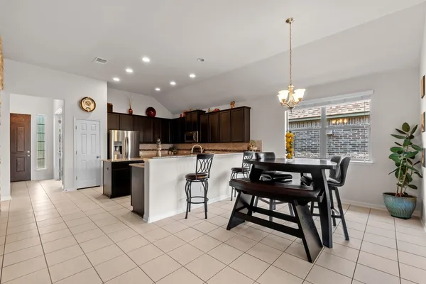 a kitchen with a table chairs refrigerator and microwave
