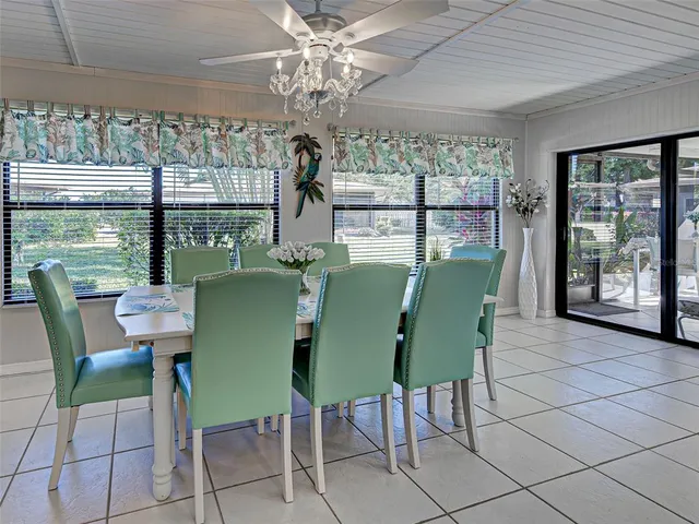 a kitchen with stainless steel appliances kitchen island granite countertop a refrigerator a sink a stove top oven a dining table and chairs with wooden floor