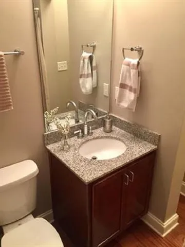 a bathroom with a granite countertop sink a toilet and a mirror