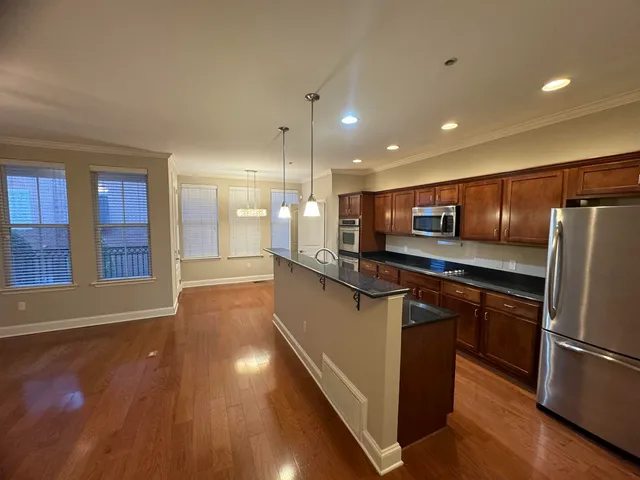 a large kitchen with stainless steel appliances a large counter top a stove and a refrigerator