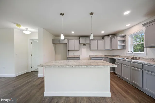 a large kitchen with stainless steel appliances granite countertop a sink a stove a refrigerator and a island with wooden floor