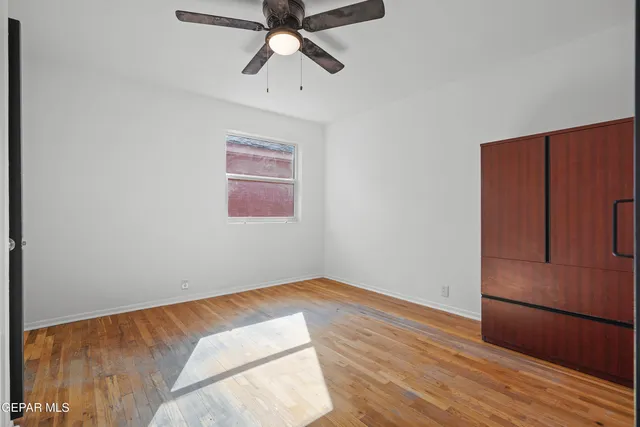 an empty room with wooden floor closet and windows