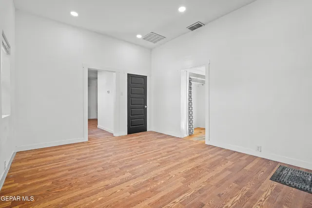 a view of an empty room with wooden floor and closet