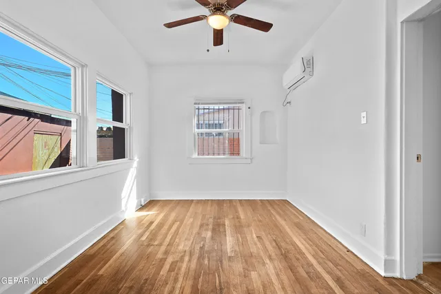 a view of empty room with wooden floor and fan
