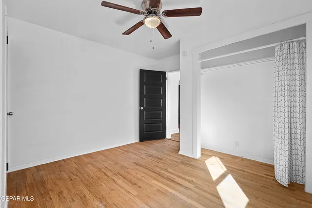 a view of a room with wooden floor and ceiling fan