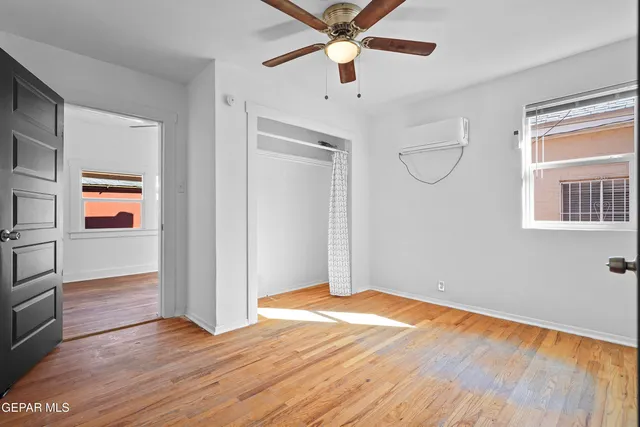 a view of empty room with wooden floor and fan