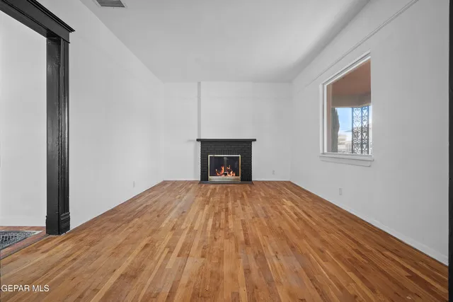 a view of empty room with wooden floor and fireplace