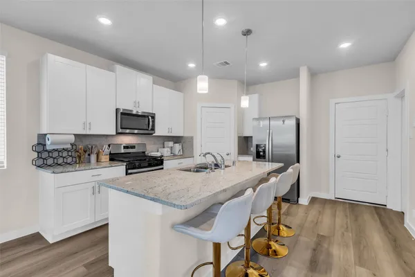 a kitchen with stainless steel appliances granite countertop a kitchen island hardwood floor and a sink