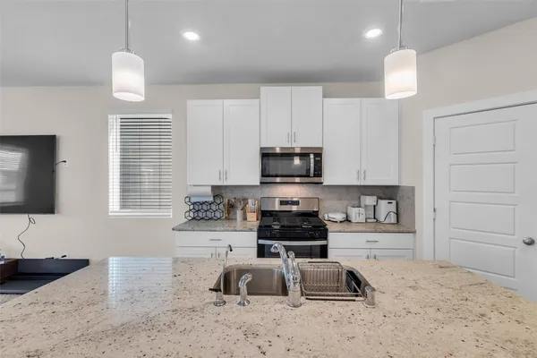 a kitchen with stainless steel appliances granite countertop a sink a stove a microwave a refrigerator and cabinets