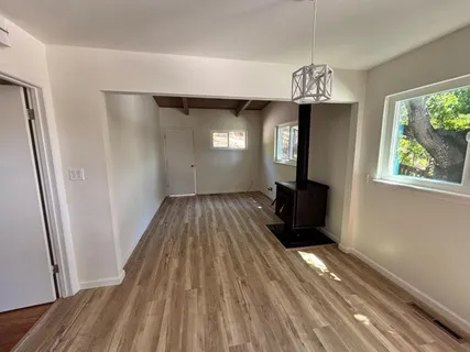 a view of a room with wooden floor a kitchen space and a window
