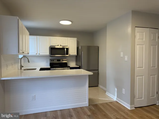 a kitchen with stainless steel appliances a refrigerator a sink a stove a microwave and wooden floors