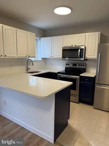 a kitchen with stainless steel appliances granite countertop a sink a stove a refrigerator a center island and cabinets