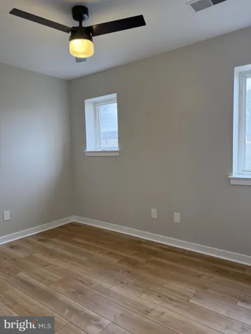 en empty room with wooden floor and windows