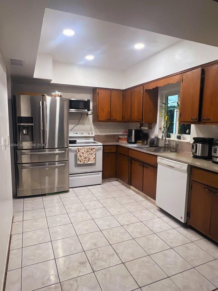 6492 Southwest 25th Street Miramar, FL 33023 - Photo 3 of 9 a kitchen with stainless steel appliances granite countertop a sink counter space cabinets and a large window