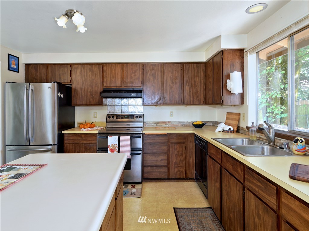 3619 Southeast 19th Court Renton, WA 98058 - Photo 7 of 21 a kitchen with a refrigerator a sink a stove a microwave and wooden cabinets