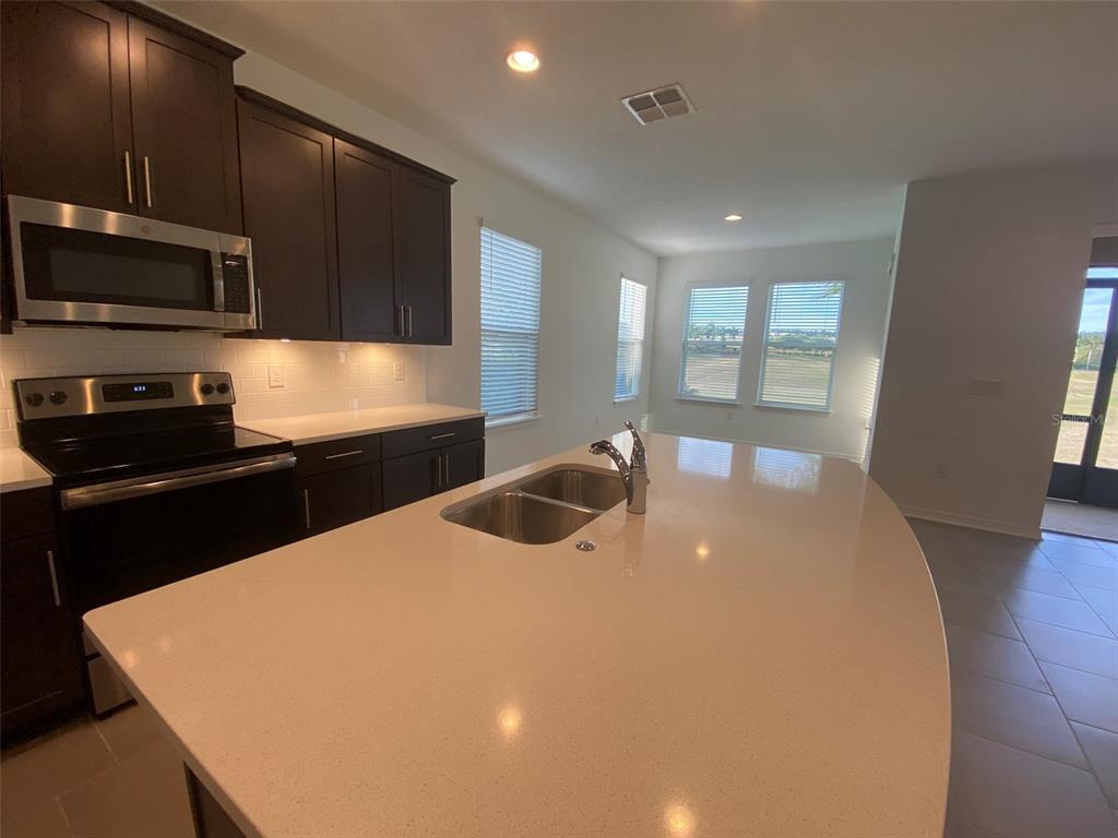 7047 Oxbow Road Minneola, FL 34715 - Photo 12 of 33 a kitchen with stainless steel appliances a sink a stove a microwave a refrigerator a sink and cabinets