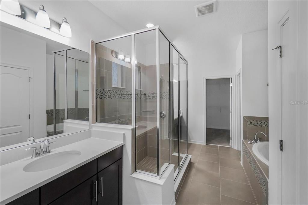 7047 Oxbow Road Minneola, FL 34715 - Photo 16 of 33 a bathroom with a shower sink and mirror