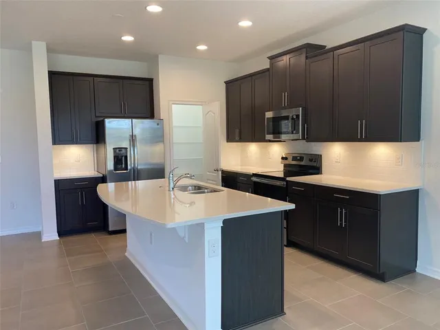 a kitchen with kitchen island stainless steel appliances a sink and a refrigerator