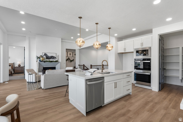 624 North Legend Circle, Unit 480 Mapleton, UT 84664 - Photo 34 of 34 Kitchen with open floor plan, a kitchen bar, stainless steel appliances, white cabinets, and light wood finished floors