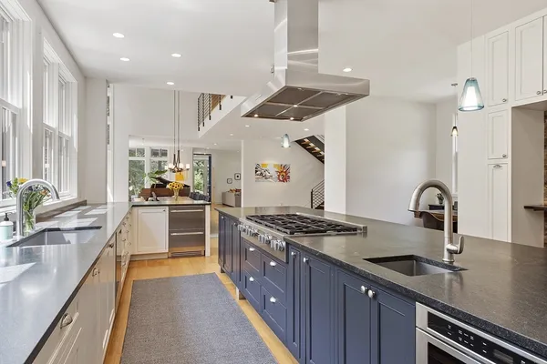 an open kitchen with granite countertop a stove and white cabinets