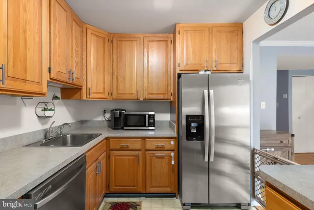 a kitchen with stainless steel appliances granite countertop a refrigerator a sink and white cabinets