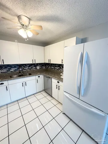 a kitchen with granite countertop a refrigerator and a sink
