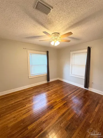 a view of empty room with wooden floor and fan