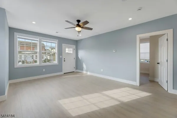 an empty room with windows and ceiling fan