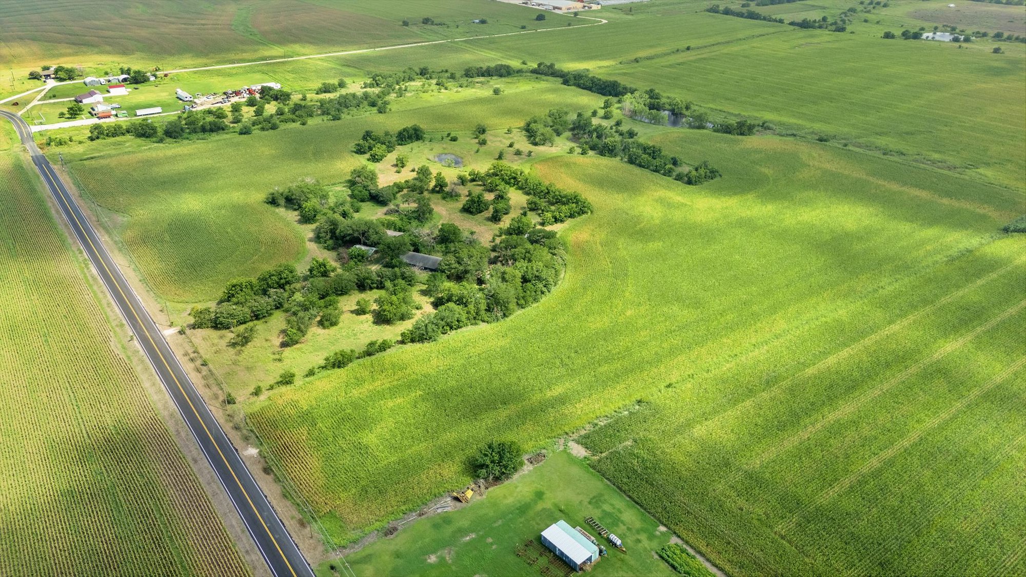 14201 Lund - Carlson Road Coupland, TX 78615 - Photo 5 of 40 An aerial perspective reveals verdant fields with a winding road leading to distant structures, perfect for agricultural pursuits.