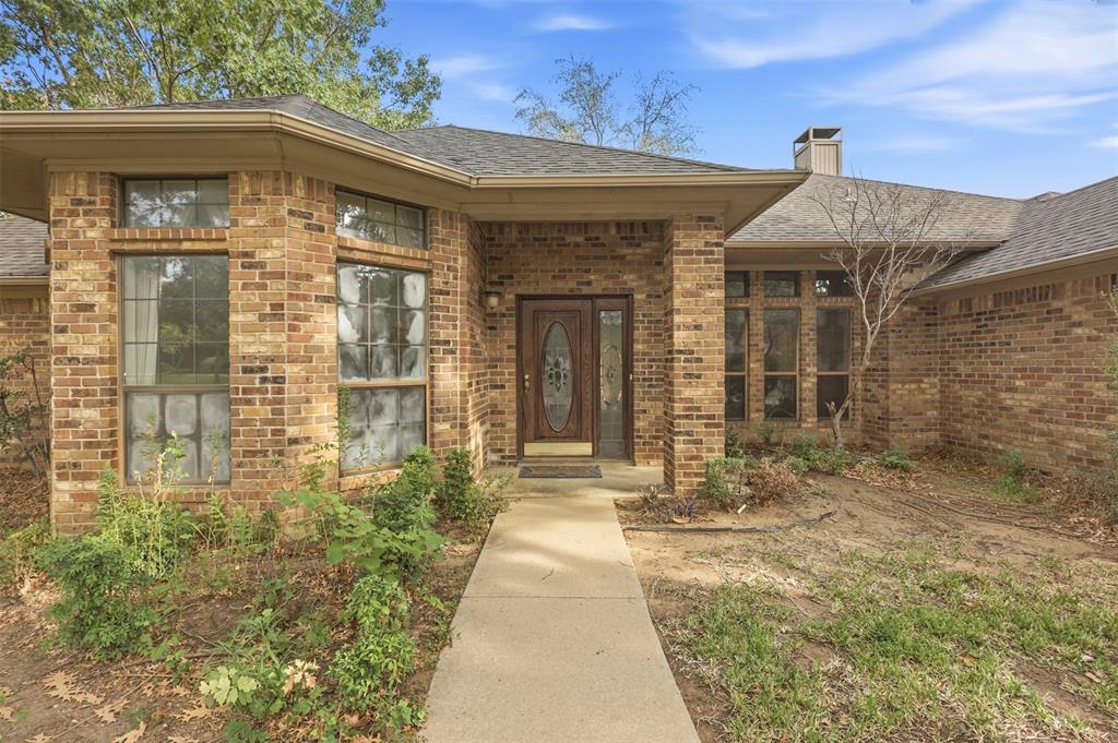 37 Timbergreen Circle Denton, TX 76205 - Photo 6 of 31 Brick exterior with a dark shingle roof and a covered entryway