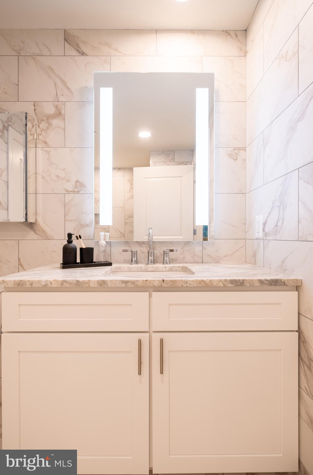 2301-61 John F Kennedy Boulevard, Unit 104 Philadelphia, PA 19103 - Photo 26 of 47 a bathroom with a sink and a mirror