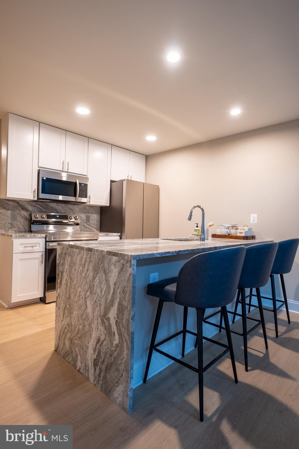 2301-61 John F Kennedy Boulevard, Unit 104 Philadelphia, PA 19103 - Photo 5 of 47 a kitchen with stainless steel appliances kitchen island granite countertop a stove a sink a refrigerator with a dining table and chairs
