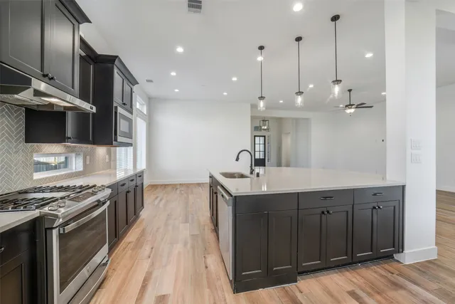 a kitchen with stainless steel appliances granite countertop a sink a stove and a wooden floors