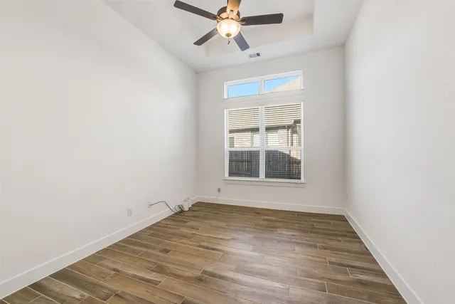an empty room with a window and ceiling fan
