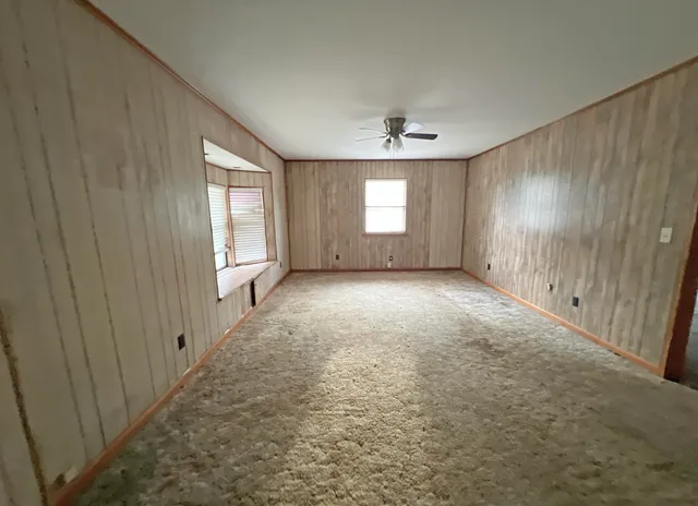 en empty room with windows and chandelier fan