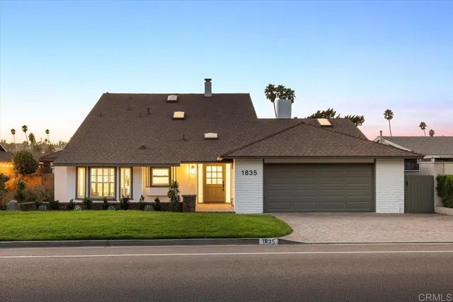 a front view of a house with a yard and potted plants