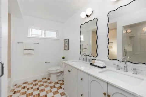 a bathroom with a double vanity sink toilet mirror and shower