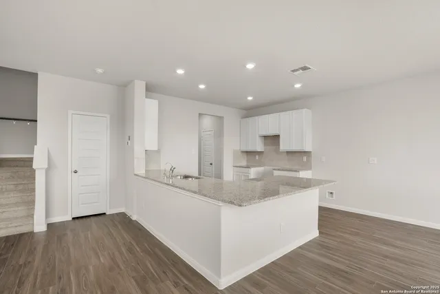 a large kitchen with stainless steel appliances kitchen island a large counter top and a wooden floors